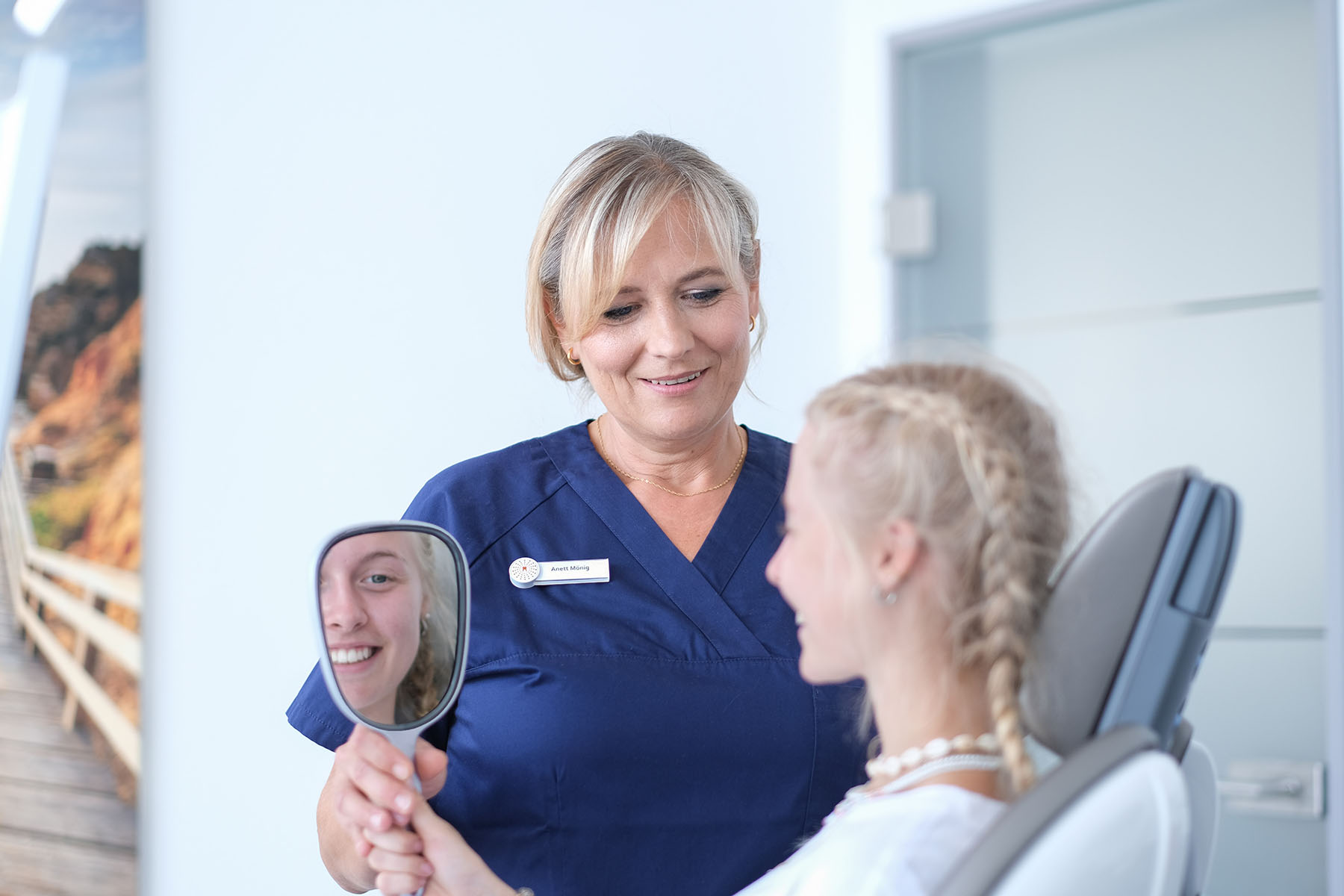 ZMF hält Spiegel Patientin im Zahnarztstuhl hin